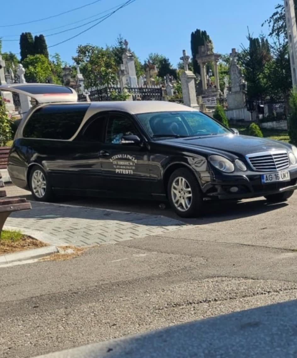Mașina funerară neagră, oprită la cimitir