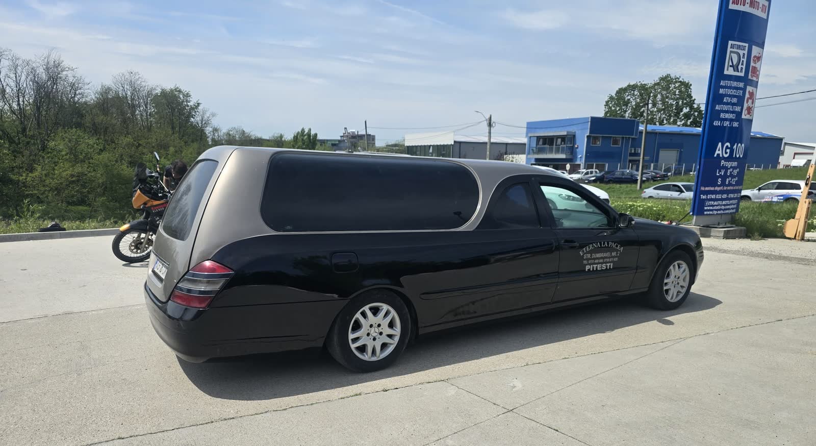Mașina funerară a firmei, cu numele și adresa scrise pe caroserie
